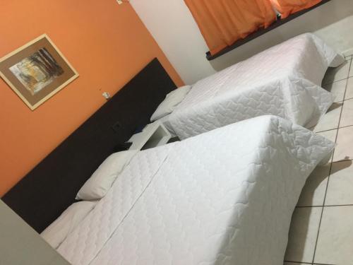 two beds with white comforters in a bedroom at HOTEL ITACAIUNAS in Marabá