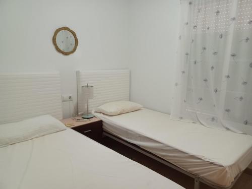 2 camas en una habitación con un reloj en la pared en AS019 2-Bedroom Casa Calypso - in Calas del Pinar, en San Juan de los Terreros