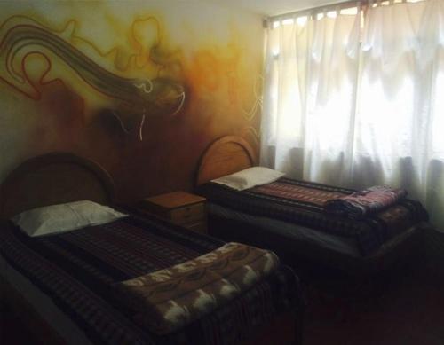 a bedroom with two beds and a window with curtains at La Casa Suiza in Huanchaco