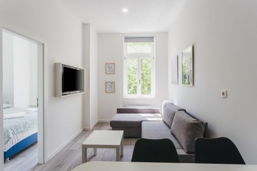a white living room with a couch and a bed at Mika Apartment and Studios in Zagreb