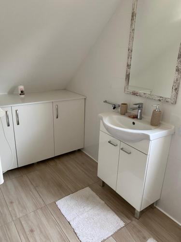 uma casa de banho branca com um lavatório e um espelho em Nasz Dom Pilchy em Pilchy