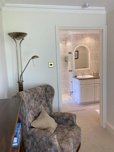 a living room with a chair and a bathroom at Exclusive 2 Bedroom Apartment with Summer House and Hot Tub in Daventry