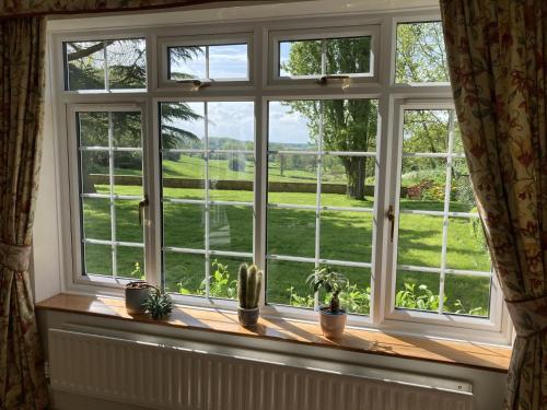 a window with a view of a green yard at Exclusive 2 Bedroom Apartment with Summer House and Hot Tub in Daventry