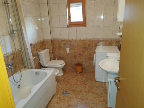 een badkamer met een bad, een toilet en een wastafel bij AK apartments in Kamenjača