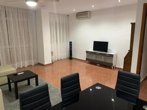 een woonkamer met een tv en een tafel en stoelen bij Room Valdeolleros in Córdoba