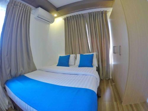 a bedroom with a large bed with blue pillows at Stylish Townhouse in Balanga City Quiet Neighborhood in Balanga