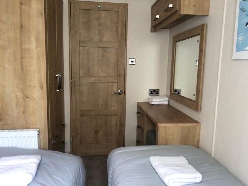 a room with two beds and a mirror and a door at Large and comfortable, stylish caravan. in Bembridge
