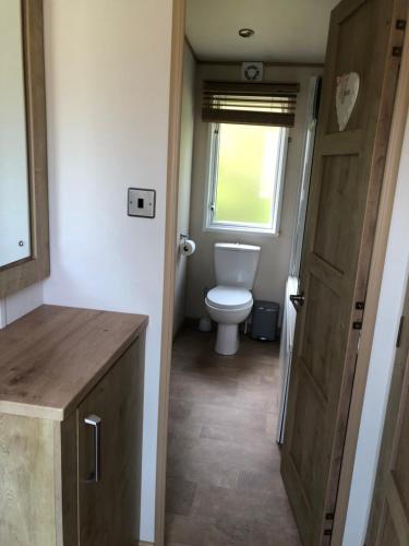a small bathroom with a toilet and a window at Large and comfortable, stylish caravan. in Bembridge