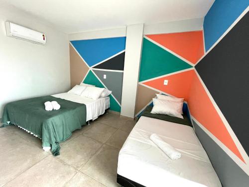 a room with two beds and a colorful wall at Sophia I - Praia Grande in Arraial do Cabo