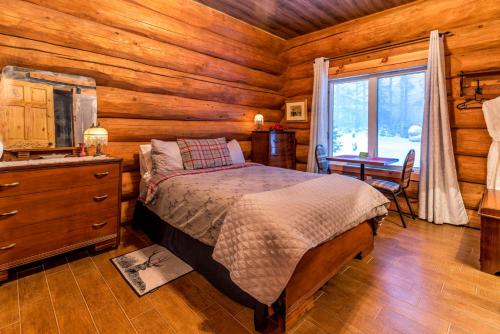 a bedroom with a bed in a log cabin at Domaine de La Giroux-ette in La Patrie