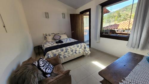 a bedroom with a bed and a couch and a window at Hospedagem Cachoeira do Tabuleiro in Cachoeira do Tabuleiro