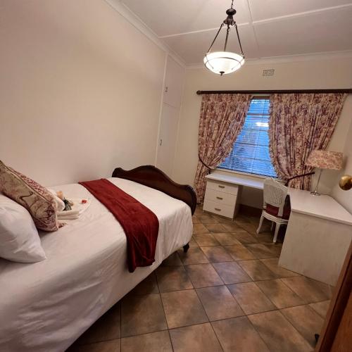 1 dormitorio con cama, escritorio y ventana en Peaceful@Swansea In Rosebank-Parkwood, en Johannesburgo