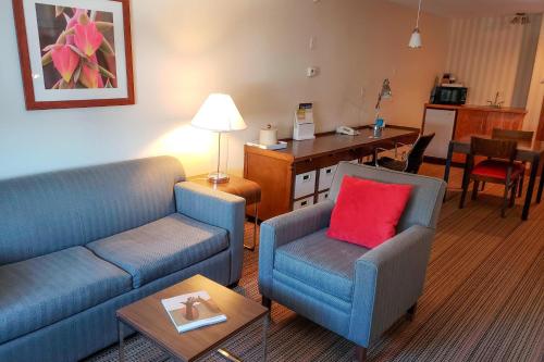 a living room with two blue couches and a red pillow at Prestige Prince George Lodge in Prince George