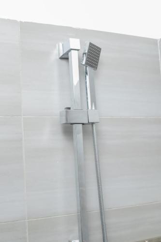 a shower in a bathroom next to a white wall at Airport Studio Gym pool fast WIFI Ideal for digital nomads Syokimau in Syokimau