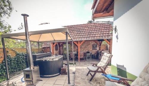 a patio with an umbrella and a hot tub at Padláskincsek Vendégház in Nagybörzsöny