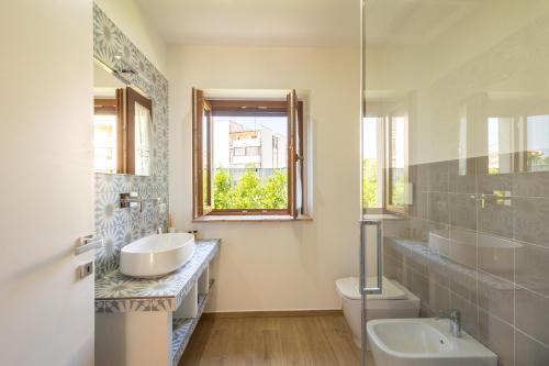 a bathroom with two sinks and a toilet and a window at B&B Podere Curtatone in Grosseto