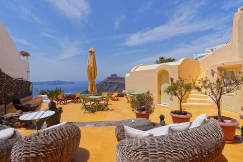 a patio with chairs and tables and a view of the ocean at Sensyo Traditional Caves in Firostefani