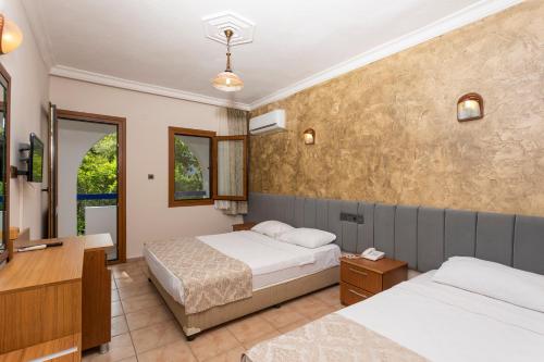 a hotel room with two beds and a desk at Gumbet Anil Beach in Gümbet