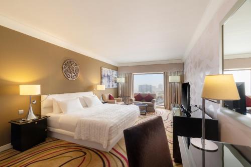 a bedroom with a bed and a living room at Le Meridien Jeddah in Jeddah