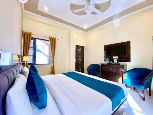 a bedroom with a bed and a tv and blue chairs at Tapovan New Residency By FTP Hotels in Rishīkesh