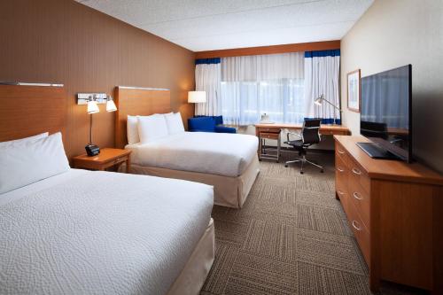 a hotel room with two beds and a flat screen tv at Four Points by Sheraton San Diego in San Diego
