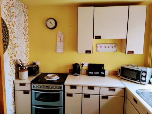 a kitchen with a stove and a clock on the wall at House - Alton Towers,Peak District,Wildlife Park in Leek
