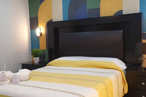 um quarto com uma cama grande com lençóis amarelos e brancos em La Soley, One-Bedroom Apartment em Oaxaca de Juárez