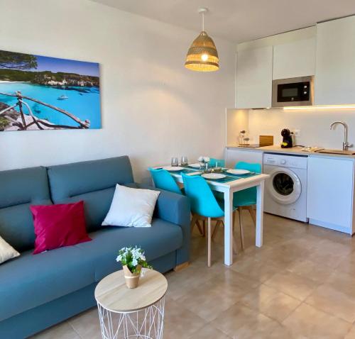 uma sala de estar com um sofá azul e uma mesa em Apartamento Sa Farola em Cala en Blanes