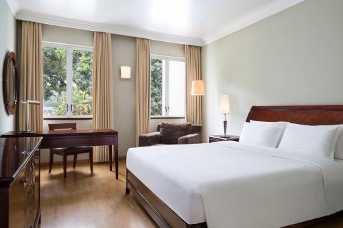 a bedroom with a large white bed and a desk and a chair at Four Points by Sheraton Arusha, The Arusha Hotel in Arusha