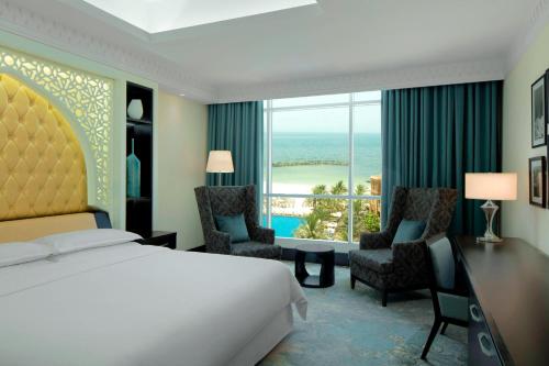 a hotel room with a bed and a desk and chairs at Sheraton Sharjah Beach Resort and Spa in Sharjah