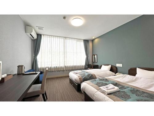 a hotel room with two beds and a desk at Tsukioka Onsen Furinya - Vacation STAY 55986v in Shibata