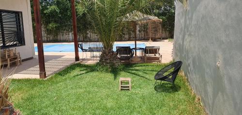 einen Garten mit einem Tisch, Stühlen und einem Pool in der Unterkunft Villa avec piscine marrakech in Marrakesch