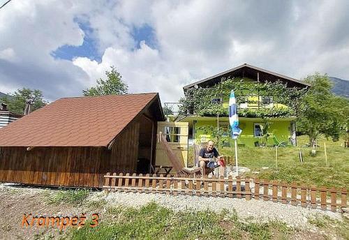 a man sitting in front of a small house at Krampez in Kobarid