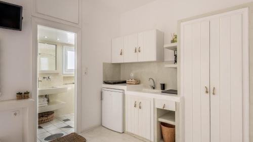 una cocina blanca con armarios blancos y fregadero en Litsa Malli Rooms, en Pollonia