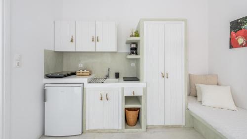 a small kitchen with white cabinets and a sink at Litsa Malli Rooms in Pollonia