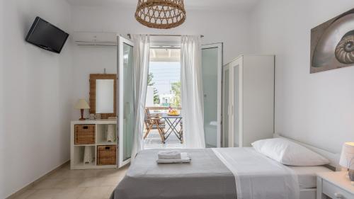 a white bedroom with a bed and a balcony at Litsa Malli Rooms in Pollonia