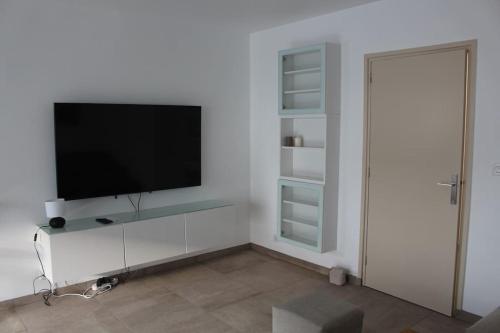 a living room with a flat screen tv on a white wall at Appt 4 pers avec parking privé gratuit Le Touquet in Le Touquet-Paris-Plage