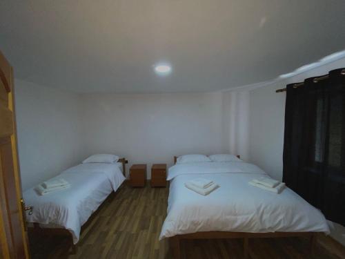 two beds in a room with white sheets at Guesthouse Rexhepi in Kolgecaj