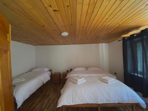 two beds in a room with a wooden ceiling at Guesthouse Rexhepi in Kolgecaj