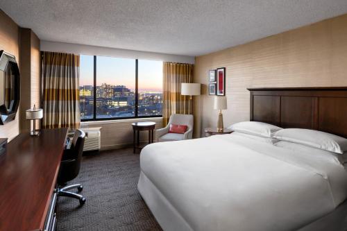 Habitación de hotel con cama blanca grande y escritorio. en Sheraton Philadelphia University City Hotel, en Filadelfia