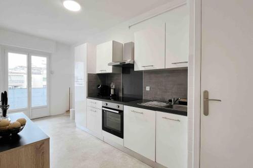 une cuisine avec des armoires blanches et des comptoirs noirs dans l'établissement L’Évasion tropicale à cannes (wifi - Netflix), au Cannet