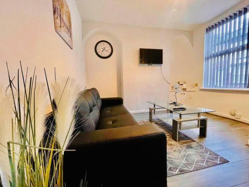 a living room with a couch and a clock on the wall at Brand New 2-BR Home Close to the City Centre in Liverpool