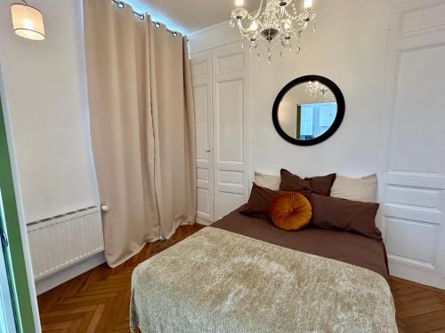 Dormitorio con cama con espejo y lámpara de araña en Appartement de charme en plein coeur de Rouen, en Rouen
