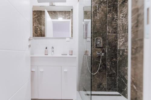 ein weißes Bad mit einer Dusche und einem Waschbecken in der Unterkunft Boutique Apartment Mostar in Mostar