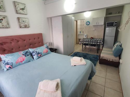a bedroom with a large bed and a kitchen at Tia's Place in Krugersdorp