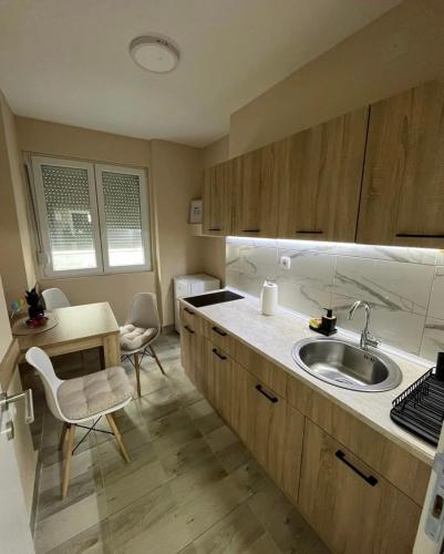 a kitchen with a sink and a table and chairs at Apartman Smile in Čačak