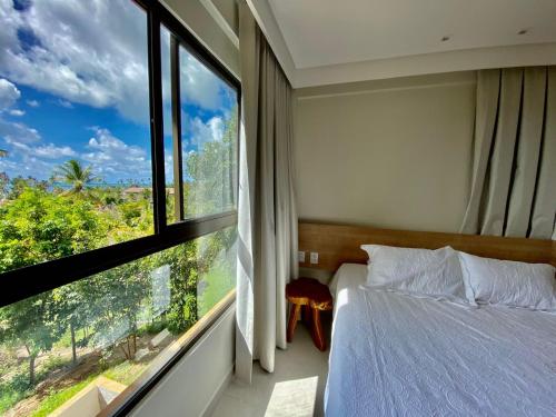1 dormitorio con cama y ventana grande en Flat luxo 04 torre 06 Eco Resort Carneiros en Tamandaré