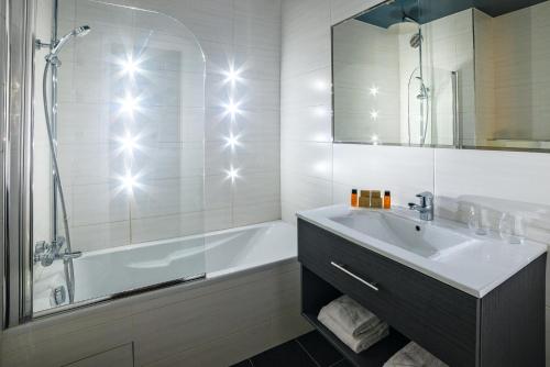 a bathroom with a tub and a sink and a bath tub at Hotel Residence Europe & Spa in Clichy