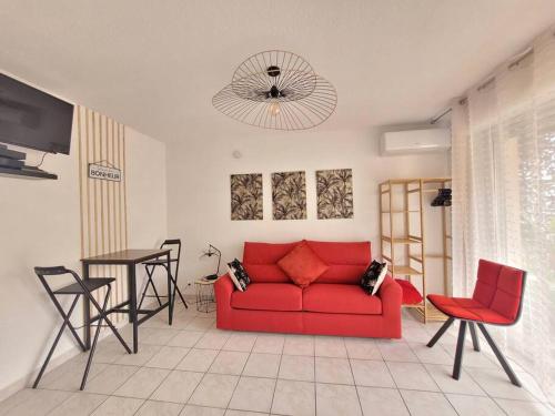 un salon avec un canapé rouge et une table dans l'établissement Studio Lucia - Vue mer, à Saint-Aygulf