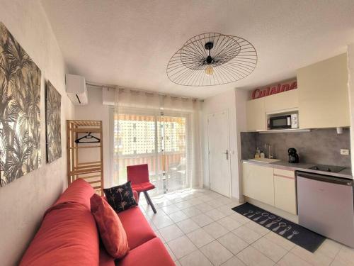 a living room with a red couch and a kitchen at Studio Lucia - Vue mer in Fréjus